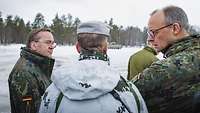 Merz and Pistorius talking with soldiers in the exercise area in winter conditions.