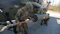 Ein Soldat schiebt eine Rakete in den Waffenwerfer eines Kampfhubschraubers Tiger.