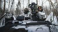 Zwei Soldaten sitzen in einem Fahrzeug Wiesel mit Waffensystem MELLS im verschneiten Wald.