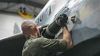 Ein Techniker baut die Bordkanone in den Eurofighter ein