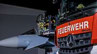 Ein Feuerwehrfahrtzeug steht im Dunkeln vor einem Eurofighter