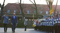 Der Bundeskanzler und ein Soldat gehen an den angetretenen Soldaten vorbei