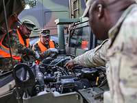 Military personnel repair a vehicle