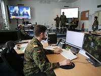 A service member is sitting at a computer