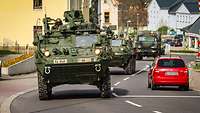Military vehicles pass through a small town.