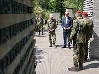 Friedrich Merz standing in front of steles in the Forest of Remembrance together with service personnel.