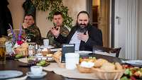 Ein Militärrabbiner mit Kippa an einem gedeckten Tisch mit Soldatinnen und Soldaten