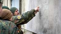 Soldaten besprechen an einer Wand die Aufstellung von Fahrzeugen.