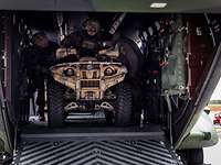 A soldier is driving a quad out of a helicopter