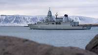 Das Schiff Fregatte Sachsen nach dem Auslaufen, im Hintergrund das verschneite Island.