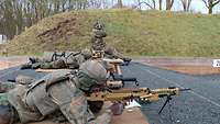 Drei Soldaten liegen nebeneinander und schauen durch die Zieloptik aufgestellter MG5.