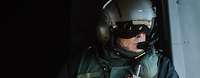 Ein Soldat sitzt in der Kabine eines Helikopters. Die Schiebetür der Kabine ist offen.