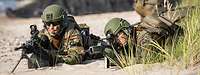 Zwei Soldaten vom Seebataillon liegen mit íhren Waffen in einer Stellung am Strand.