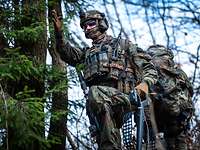 Ein Soldat zeigt seinen Kameraden im Wald die Richtung auf.