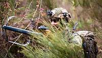 Ein LEKE-Soldat mit einem Gerät zur elektronischen Aufklärung hockt halb versteckt im Gebüsch.