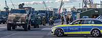 Soldaten und Polizei stehen am Hafen neben Militärfahrzeugen