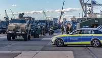 Soldaten und Polizei stehen am Hafen neben Militärfahrzeugen