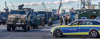 Soldaten und Polizei stehen am Hafen neben Militärfahrzeugen