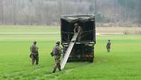 Soldaten verlegen Minen mithilfe einer Rutsche von der Ladefläche eines Fahrzeugs aus.