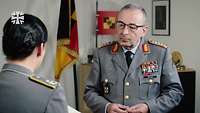Der Generalinspekteur Carsten Breuer spricht mit einer Soldatin in einem Büro.