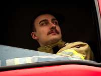 Ein Mann am Steuer eines Feuerwehrfahrzeuges schaut aus dem Seitenfenster.