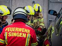 Mehrere Feuerwehrmänner öffnen mit einem Spreizer eine Autotür.