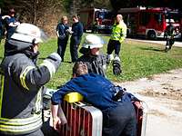 Feuerwehrmänner kümmern sich um einen verletzten Mann, sein Rücken ist von einem Rohr durchbohrt. 