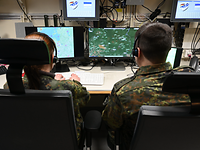 Zwei Soldaten sitzen vor Bildschirmen.