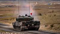 Ein Panzer Leopard schießt auf der Schießbahn. Rauch steigt auf.