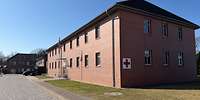 Zweistöckiges, rotes Backsteingebäude mit einem Roten Kreuz auf weißem Grund an der Fassade