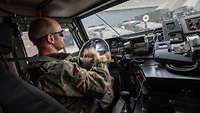 Ein Soldat sitzt am Lenkrad im Fahrerraum eines Militärfahrzeuges.