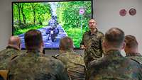 Ein Soldat, vor einem Bildschirm, der anderen Soldaten eine Verkehrssituation zeigt.
