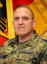 Porträt eines Soldaten vor einer Truppenfahne