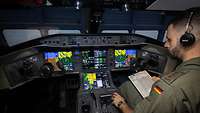 Ein Pilot sitzt mit einer Checkliste in der Hand im Cockpit.