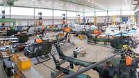 Blick in eine Ausbildungshalle mit verschiedenen Flugzeugen und Hubschraubern