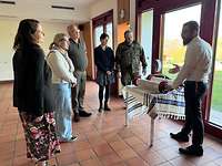 Ein Rabbiner mit Kippa steht mit Interessierten, die teilweise mit Uniform sind, um eine Torarolle.