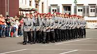 Eine Formation von Soldatinnen und Soldaten im Dienstanzug marschiert auf einem Marktplatz ein.