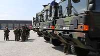 Vor mehreren Bundeswehr-Lkw steht eine Gruppe Soldaten