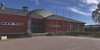 Rotes, flaches Gebäude mit halbrundem, großem Dach über dem Eingang