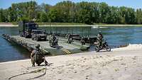 Militärfahrzeuge verlassen eine militärische Fähre auf einem Fluss