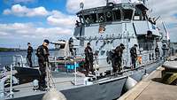 Soldaten lösen die Leinen zum Ablegen auf einem grauen Schiff