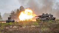 Der Kampfpanzer Leopard gibt einen Schuss ab, an der Kanonenmündung entsteht ein Feuerball.