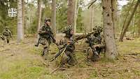 Soldaten knien und laufen im Wald.