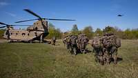 Mehrere Soldaten bringen andere, die Verwundete spielen, zu einer CH-47.