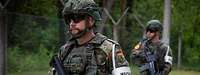 Zwei bewaffnete Soldaten mit weißen Armbinden, darauf das Wort Wache, laufen Streife.