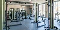 Blick in einen Raum mit verschiedenen Fitnessgeräten aus grün angestrichenem Metall
