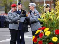 Three soldiers hold a flag