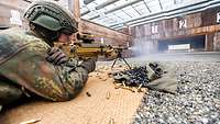 Ein Soldat liegt auf einer Bastmatte und schießt mit aufgestelltem MG, vor ihm die Schießanlage.