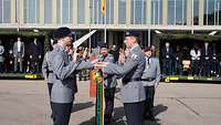 Auf einem Appellplatz legen sechs Soldaten jeweils eine Hand auf die abgesenkte Truppenfahne.