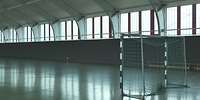 Blick in eine Halle mit halbhohen Fenstern und einem Balltor auf glattem Boden